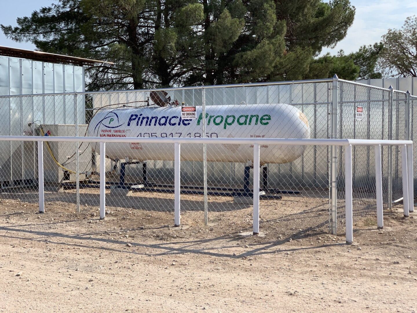 A sign that says pinnacle tropone in front of a fence.