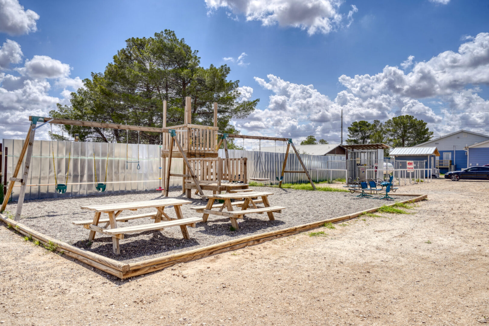 A playground with wooden benches and swings.